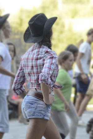Girl dressed like cowgirl, with denim shorts and cowboy hat,  dancingのeditorial素材