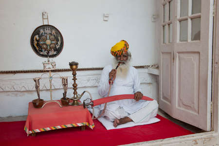 JODHPUR, INDIA - 19 OCTOBER 2013 - Unidentified aged typical indian man with yellow turban smoking a...