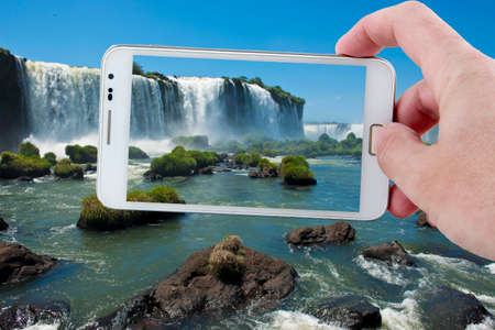 Taking a picture at the footbridge over the magnificent garganta del diablo at the iguazu falls, one of the seven natural wonders of the worldの写真素材