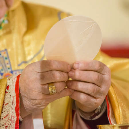 Bishop officiation mass during eucharist with holy bread and goblet
