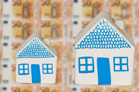 Two different width houses on a background of many 50 euro banknotesの写真素材