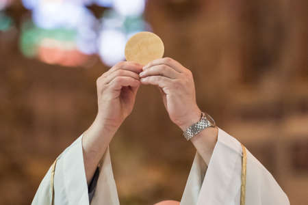 Minister showing the holy bread during the rite of the Holy Communion during the catholic massの写真素材