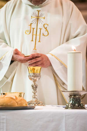 Minister showing the holy bread during the rite of the Holy Communion during the catholic massの写真素材
