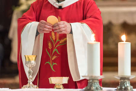 Minister showing the holy bread during the rite of the Holy Communion during the catholic massの写真素材