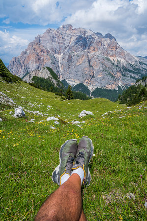Hiker resting during a trail, facing the mountains in the Dolomites near San Cassianoの写真素材