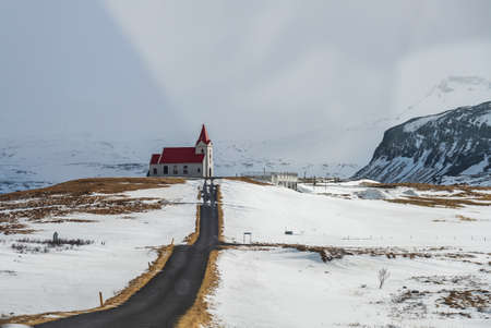 White church with red roof in the snowy landscape of Hellisandur, Iceland
