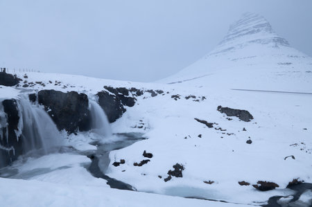 Kirkjufell Mountain and two waterfalls under the snow in Snaefellsnes Peninsula, Icelandの写真素材