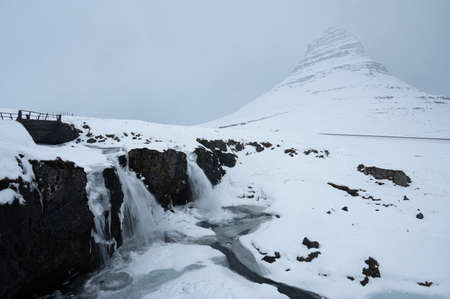 Kirkjufell Mountain and two waterfalls under the snow in Snaefellsnes Peninsula, Icelandの写真素材