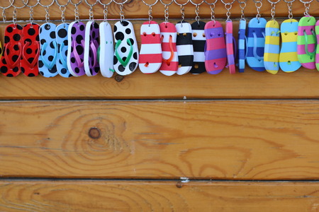 Many small sandal colorful object is a key chain decorate on wood background . space for text using .の写真素材
