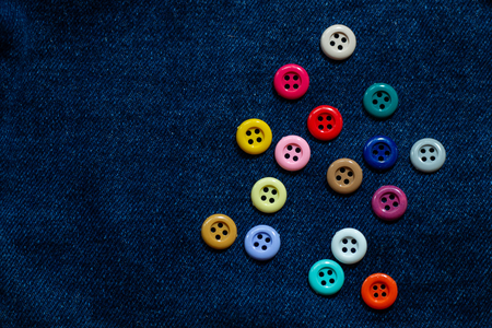 many various clasper , colorful buttons object for seamstress and sewing on blue indigo jeans .