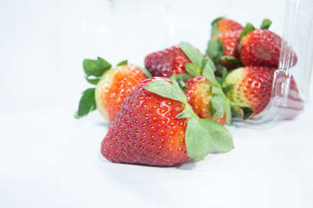 close up perfect red color strawberry . fresh fruits with green leaves , juicy ripe strawberries in box on white backgroundの写真素材