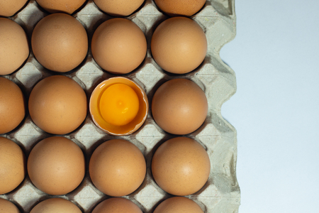 cracked chicken eggs in carton box with albumen and yolk .