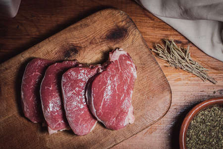 Cuts of Argentine beef on wooden board along with rosemary and oreganoの写真素材