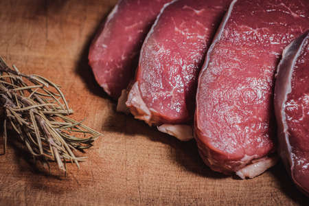 Cuts of Argentine beef on wooden board along with rosemary