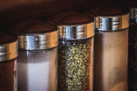 Jars with spices: paprika, oregano, salt, chia, sesame on wooden shelfの写真素材