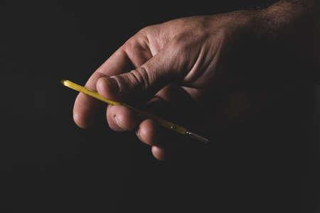 Hand handing over a thermometer with black backgroundの写真素材