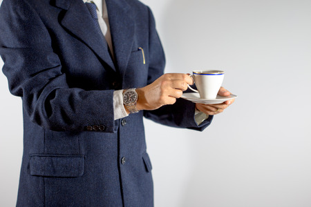Elegant man holding a cup of coffee or tea in hands, on white backgroundの写真素材