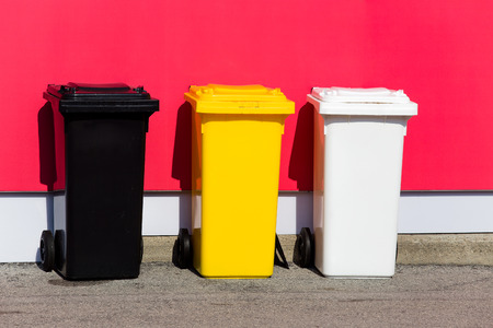 Three colored recycle bins on the street/ Black/ Yellow/ Whiteの写真素材