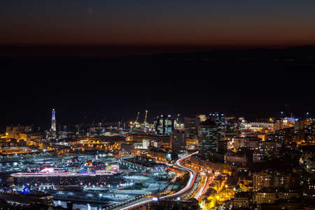 GENOA, ITALY, NOVEMBER 18,2020 - Aerial view of Genoa by night, modern buildings, the harbor with...
