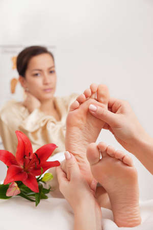 Hands of a reflexologist doing reflexology treatment on the soles of a womans feetの写真素材