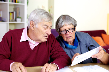 Elder couple looking at documents on the table in the living roomの写真素材