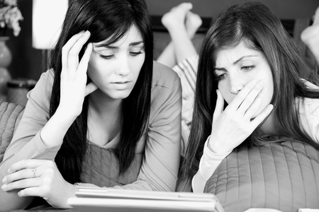 Black and white portrait of sad girlfriends in bedの写真素材