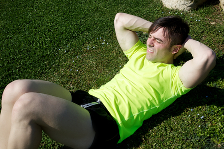 Young trainer having a hard time doing abdominalの写真素材