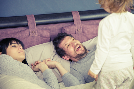 Cute family in bed playingの写真素材
