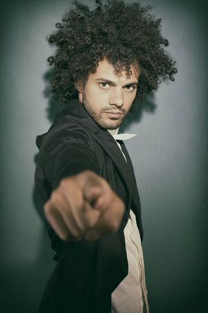 cool handsome man dress with style looking intently at camera, pointing finger