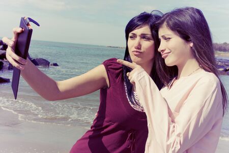 Gorgeous women taking pictures with cell phone in front of sea