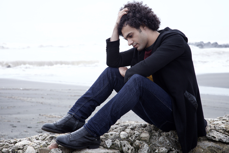 Unhappy man thinking sitting in front of the sea