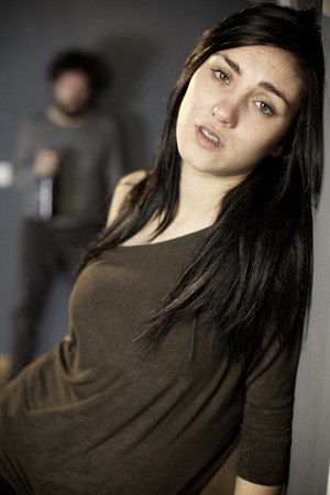 Unhappy young woman feeling bad with violent husband behind her backの写真素材