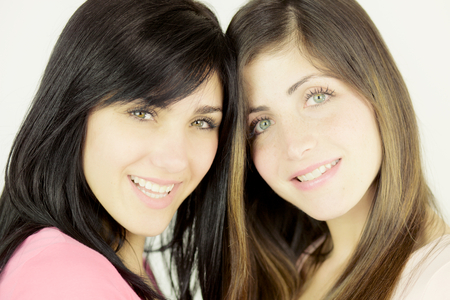 Two beautiful young women showing strong friendship looking cameraの写真素材