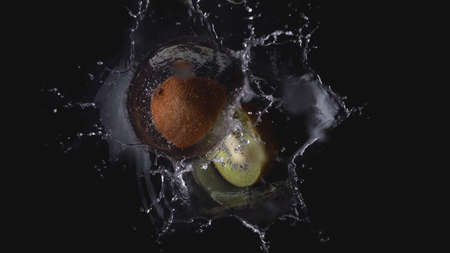 Two pieces of a kiwi falling in water - splashの写真素材