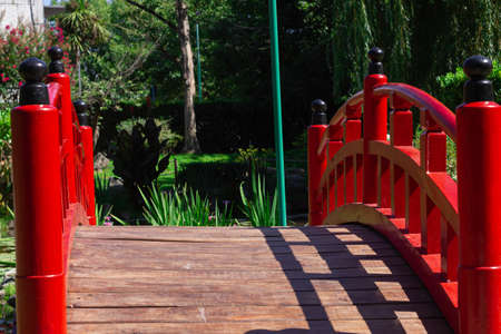 Litlle red bridge in a city park on a sunny day.の写真素材