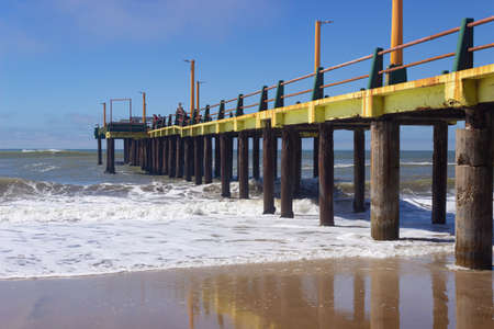 Waves hitting and old pier on a sunny day.の写真素材