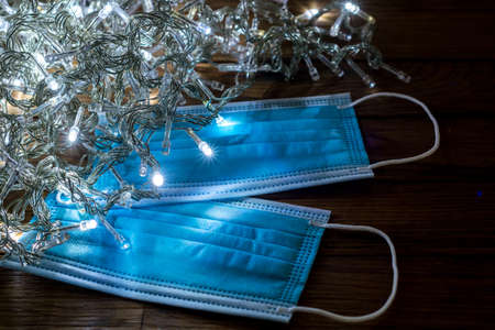 Christmas in times of coronavirus. Surgical mask over christmas lights in the dark. Covid-19