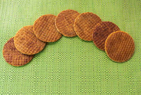 Aerial shot of stroopwafels distributed in an arc on a individual green