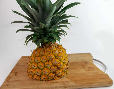 Shot of a cut pineapple on a wooden board on white