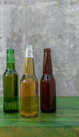 Light and dark beers in their bottles on a green wooden table with a gray background