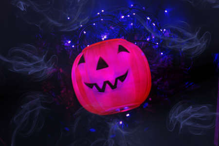 An orange pumpkin in the middle of the smoke with background lights on a branchの写真素材
