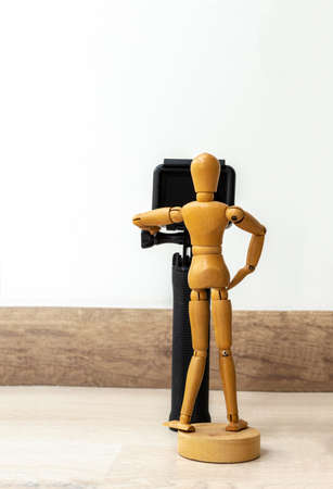 Wooden dummy with a photo and video camera on a wooden floor and white backgroundの写真素材