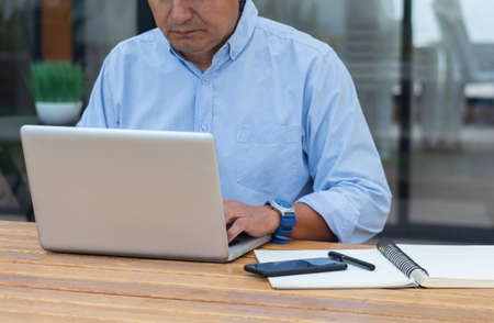 In a coworking office a man work with her laptop in a wood desk