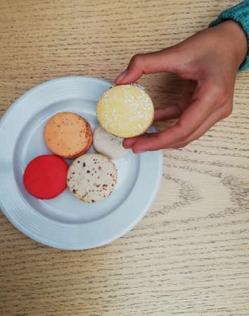 Aerial shot of macaroons on a plate with one hand taking one