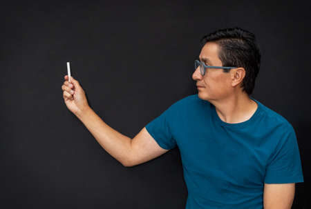 In a class a teacher points to something with chalk on a black boardの写真素材