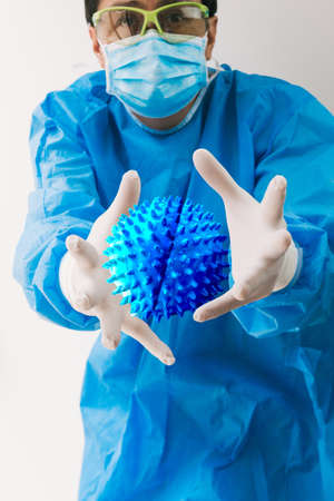 Doctor with protective gear tries to catch a magnified virusの写真素材