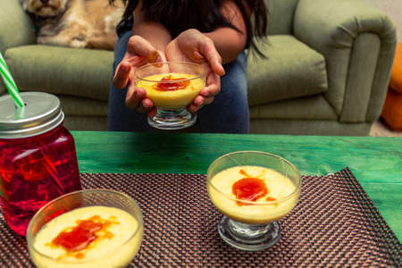 Closeup of a woman's hands sitting next to her dog holding a glass with creme bruleeの写真素材