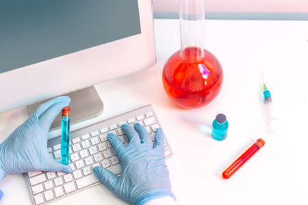 Laboratory with computer, flask, test tubes with hands holding a test tube....