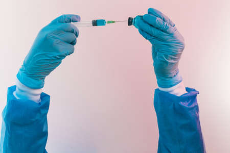 Close-up of arms holding a syringe in the hands while drawing the liquid from its container, vaccine, medicine.の写真素材