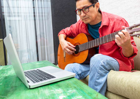 Man intently watches an internet guitar classの写真素材